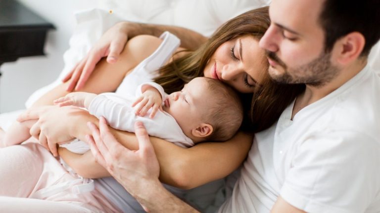 Mutter und Vater halten ihr schlafendes Baby im Arm – Ganzheitliche Hilfe bei Neurodermitis